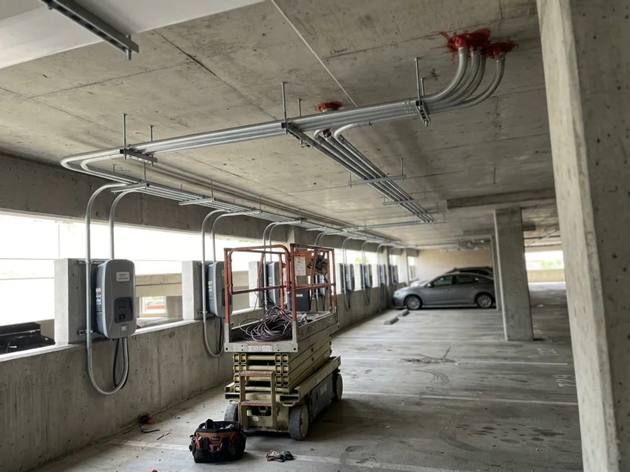 Overhead conduit run feeding EV charging stalls in a condo garage
